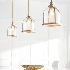 three pendant lights hanging from a ceiling in a kitchen with white walls and flooring