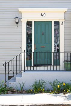 the front door of a white house with green doors