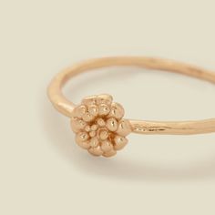 a gold ring with flowers on the side and a bead in the middle, sitting on a white surface