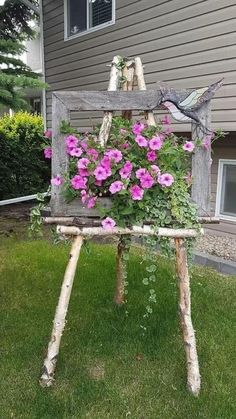 an old chair with flowers growing out of it in front of a house on the grass