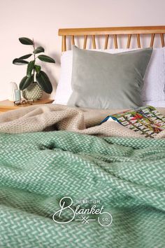 Modern mid century wooden bed piled with cosy green blankets and a paperback. There's a ficus on the nightstand. Green Bedding Aesthetic, Blanket Texture, Green Houseplants, Green Bedroom Aesthetic, Green Bedroom Decor, Modern Boho Bedroom