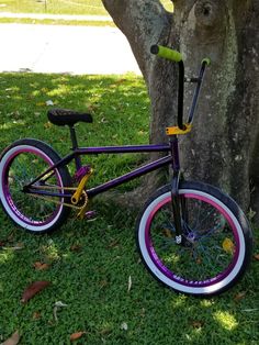 a purple and black bike parked next to a tree