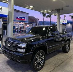 a black truck parked in front of a gas station