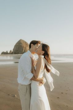 a newly married couple kissing on the beach