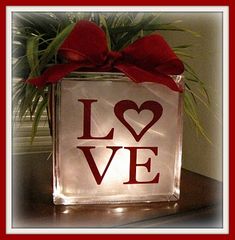 a glass block with the word love on it and a red bow tied around it