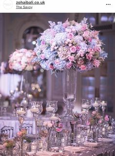 an image of a table setting with flowers in vases and wine glasses on it