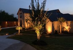 a house that is lit up at night with lights on the front and side of it