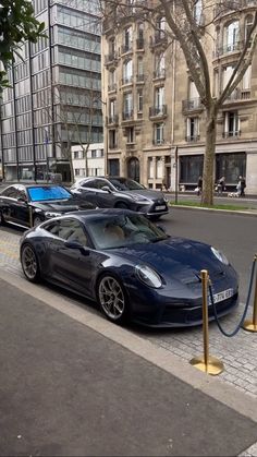 a blue sports car is parked on the side of the road in front of some buildings