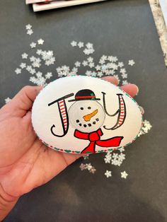 a hand holding an ornament with a snowman on it