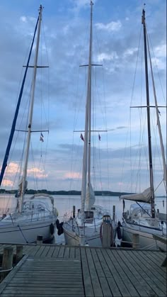 several sailboats docked at a pier on the water