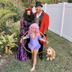 three people dressed up in costumes posing for a photo with a dog on the grass