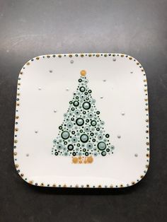 a white plate with a green and gold christmas tree design on it's side