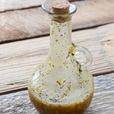 a glass bottle filled with mustard sitting on top of a wooden table covered in dirt