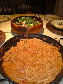 a large pan filled with pasta and salad on top of a table next to other plates