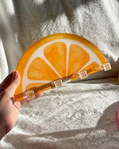 a person holding an orange slice on top of a white towel next to a pink object