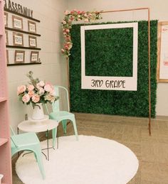 a room that has some chairs and flowers on the table in front of green wall