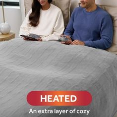 a man and woman sitting on a bed with the text heated an extra layer of cozy