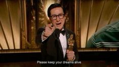 a man in a tuxedo giving a thumbs up while holding an oscar award