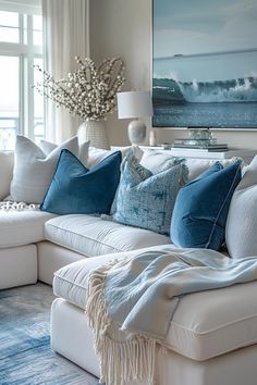 a living room filled with white couches and blue throw pillows on top of them