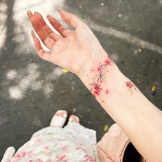 a woman's hand with a flower tattoo on her left wrist and right arm