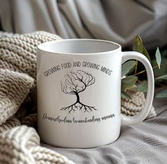 a white coffee mug with the words growing food and growing money on it next to a blanket