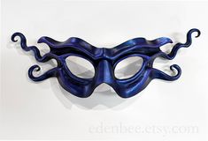 This mischevious mask is a has an impish twist to it.  It has been hand-sculpted, and hand-painted with a black base and shimmery, translucent blue / violet highlights.  A simple but dramatic piece, it will provide the perfect finishing touch to any masquerade outfit. Removable leather ties are included for wear. This mask is hand-shaped from a single piece of leather, without the use of forms or moulds.  It is lightweight, flexible, and comfortable to wear.  As each mask is an individually scul Violet Highlights, Masquerade Outfit, Mha Dr, Shape Templates, Mask Black, Bleu Violet, Hand Shapes, Blue Violet, Single Piece