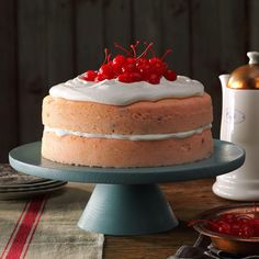 a cake with white frosting and red cherries on top sitting on a table