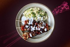 a white plate topped with meat, rice and veggies next to a fork