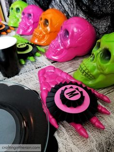 there are many different colored plastic skulls on the table and one is holding a black plate