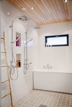 a bathroom with white walls and tile flooring next to a ladder in front of the bathtub