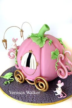 there is a cake that looks like a pink carriage with green decorations on it and an animal figurine next to it