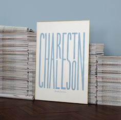 a stack of records sitting on top of a wooden table next to a framed poster