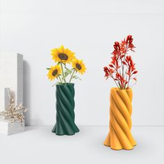 three vases with sunflowers and other flowers in them on a white surface