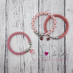 two red and white bracelets sitting on top of a wooden table next to each other