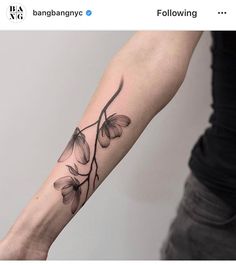 a woman's arm with flowers on it and a branch in the middle of her arm