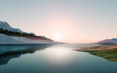 the sun is setting over a mountain lake