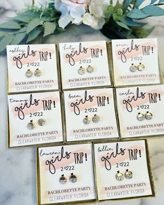 six pairs of earrings are on display in front of some white flowers and greenery