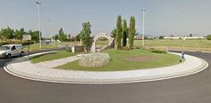 a car is parked in front of a gated entrance to a park with trees and bushes