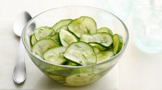 a glass bowl filled with sliced cucumbers on top of a white countertop