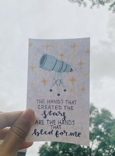 a hand holding up a piece of paper with an image of a rocket ship on it