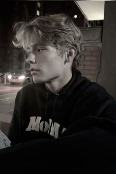 a young man sitting on top of a bench next to a building