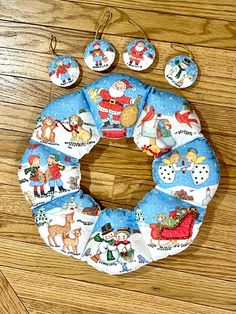 a blue christmas wreath with santa claus and other holiday decorations on it sitting on a wooden floor