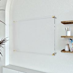 a white wall with some shelves on it and a potted plant in the corner