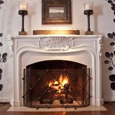 a white fireplace with candles and a painting on it's wall behind the fire place