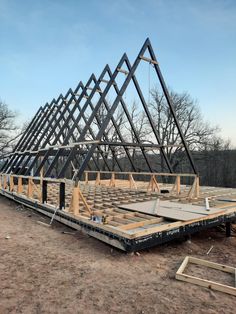 a building being built with metal beams and wooden boards on the ground in front of it