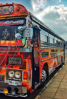 an orange and black bus parked on the side of the road next to a sidewalk