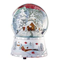 a snow globe with houses and trees in the snow, on top of a stand