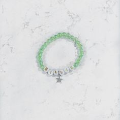 a green beaded bracelet with the word believe written on it and a star charm