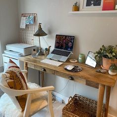 a laptop computer sitting on top of a wooden desk next to a chair and potted plant