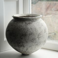 a large gray vase sitting on top of a window sill next to a window